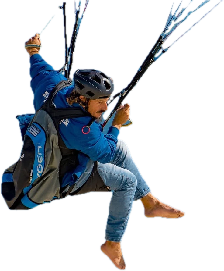 Javi Tejeiro in a pod harness, helmet on, legs kicked out barefoot, looking down at the sea far below
